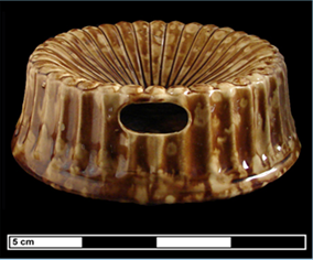 Brown and yellow mottled ceramic spittoon side view showing the hole where the tobacco juice is removed.